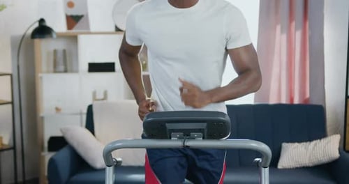 Man Running on Treadmill Wearing Headphones at Home