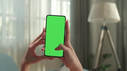 Close Up Of Hand Woman Lying On Couch Using Smartphone With Mock Up Green Screen Display