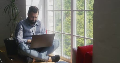 Man Working on Laptop in Sunny Window