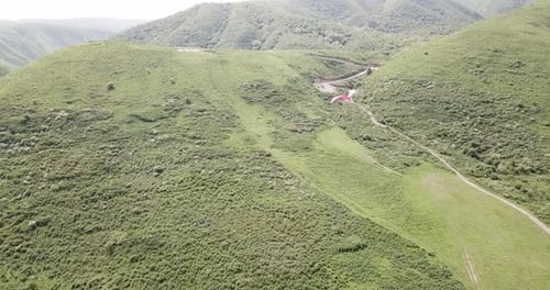 Paraglider Glides Over Hilly Landscape on a Sunny Day