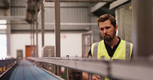 Man Inspecting Conveyor Belt in Industrial Setting