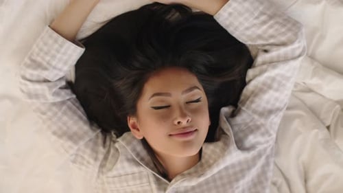 Smiling Woman Lying in Bed Wearing Pajamas