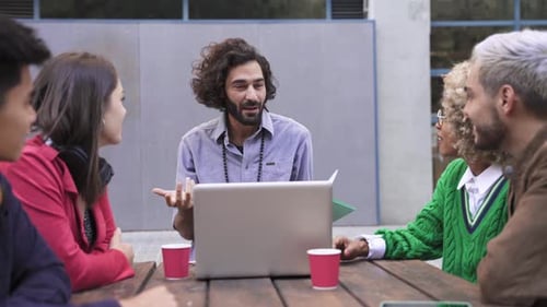 Diverse Team Discussing Project Around Laptop Outdoors