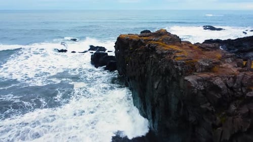Aerial Top View of Waves Break on Rocks in a Blue Ocean
