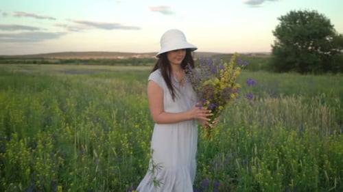 Young Woman Walking With Bouquet of Field Flowers