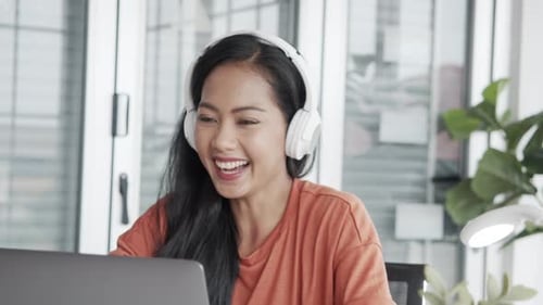 Smiling Woman in Headphones Working on Laptop