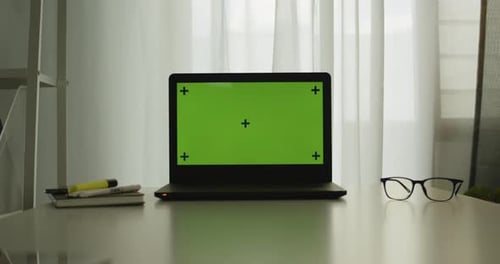 Shot of a laptop with chroma key green screen on a table in office room.