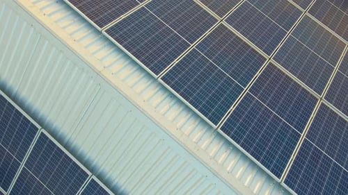 Blue photovoltaic solar panels mounted on building roof for producing clean ecological