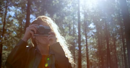 Woman Taking Photo in Forest With Vintage Camera