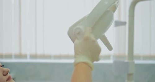 Dentist Adjusting Light Over Patient in Dental Office