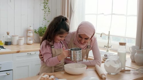 Muslim Mother And Daughter Using Flour Sifter Baking In Kitchen