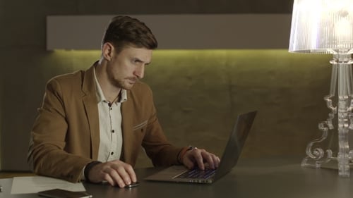 Man Works on Laptop at Desk