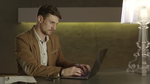 Man Types on Laptop at Desk in Office