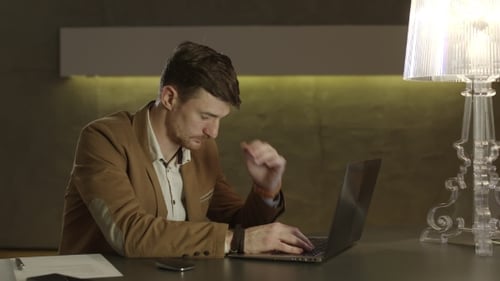 Tired Man Using Laptop at Desk Indoors