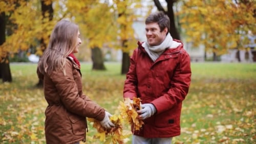 Happy Young Couple Throwing Autumn Leaves In Park 10
