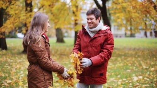 Happy Young Couple Throwing Autumn Leaves In Park 11