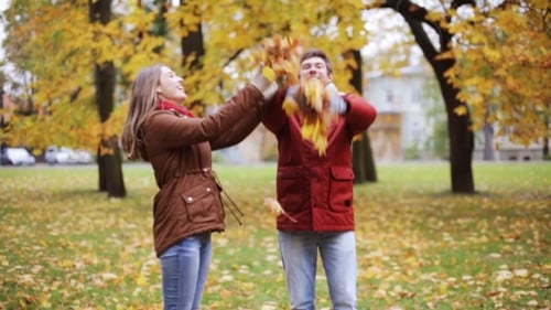 Happy Young Couple Throwing Autumn Leaves In Park 12