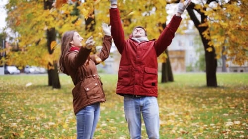 Happy Young Couple Throwing Autumn Leaves In Park 13