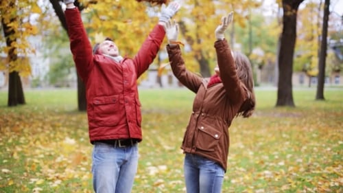 Happy Young Couple Throwing Autumn Leaves In Park 14