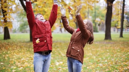 Happy Young Couple Throwing Autumn Leaves In Park 15
