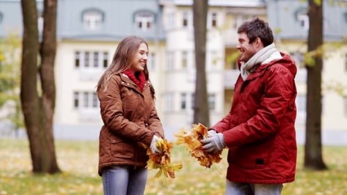 Happy Young Couple Throwing Autumn Leaves In Park 30