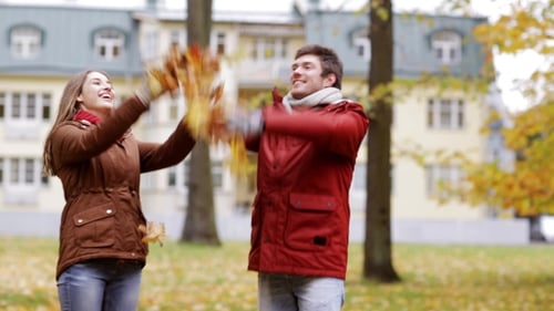 Happy Young Couple Throwing Autumn Leaves In Park 31