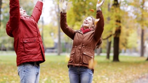 Happy Young Couple Throwing Autumn Leaves In Park 32