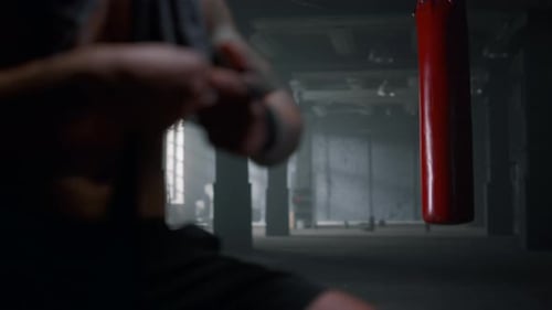 Fighter Wrapping Hands with Boxing Tapes in Gym