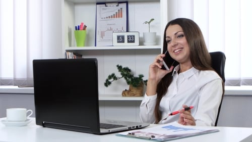 Girl is Sitting in Office and Talking on the Phone and Holding in His Hand a Handle
