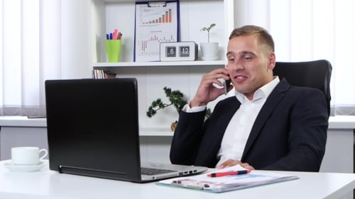 Businessman Talking On Phone In His Office And Smiling