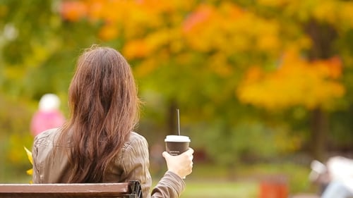 Beautiful Woman Drinking Coffee In Autumn Park Under Fall Foliage