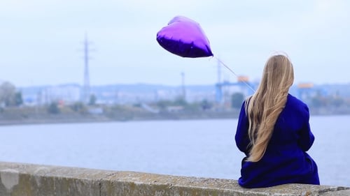 Young Woman with Heart Balloon Sitting by River