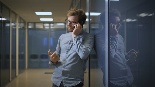 Man talking on phone in office hallway