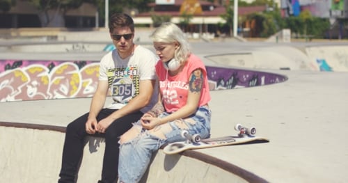 Two Young Adults Chatting at Skatepark