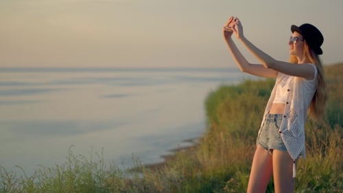 Young Woman Uses a Smartphone To Shot Video a Beautiful Sunset View