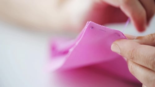 Adult Sewing Pink Fabric with Needle Close Up