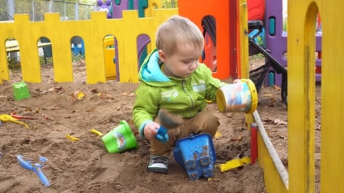 Child Plays with Toys in a Sandbox