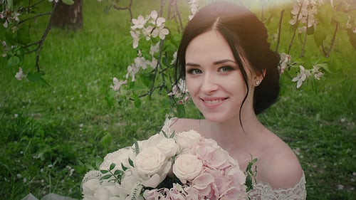 Beautiful Young Bride Holding Flowers in the Sunlight