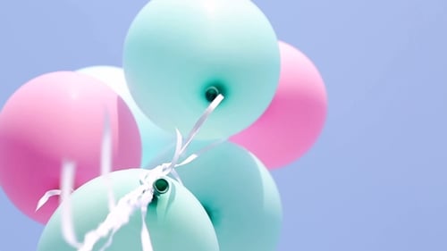 Pastel Balloons Floating Against Blue Sky