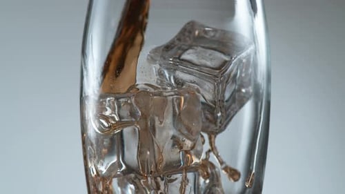 Pouring a Fizzy Brown Beverage Over Ice