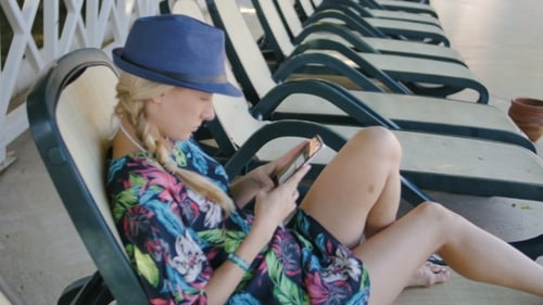Young Woman Using Cellphone While Lying On Sunbed At Hotel