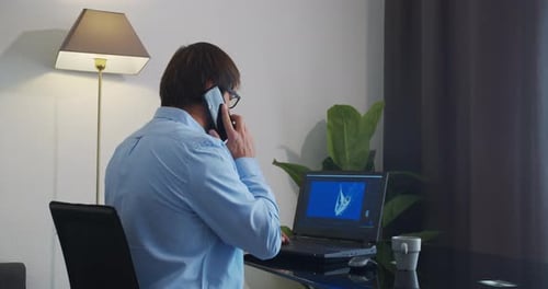 Man Working at Desk While Talking on Phone