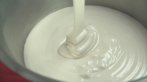 Cream Being Poured into a Silver Mixing Bowl