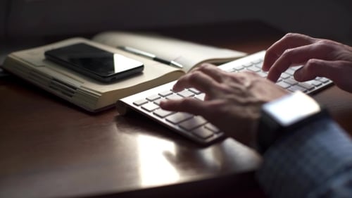 Fröhlicher junger Mann benutzt eine moderne Tastatur