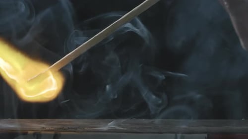 Hand Strikes Match, Ignites in Dark Setting