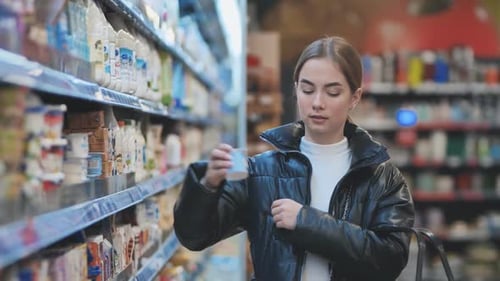 A Young Girl Chooses Dairy Products in the Store
