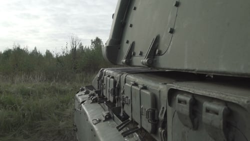Green Military Tank Moving Through Grassy Field
