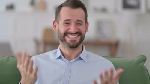 Man Celebrates Good News While Sitting on Couch