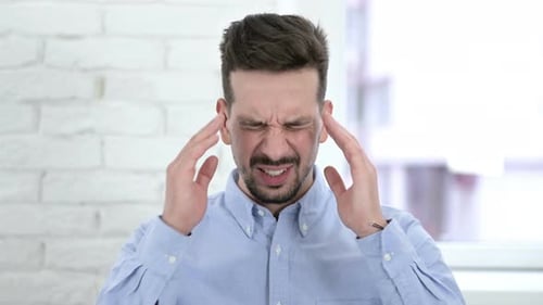 Young Adult Experiencing Headache and Rubbing Temples