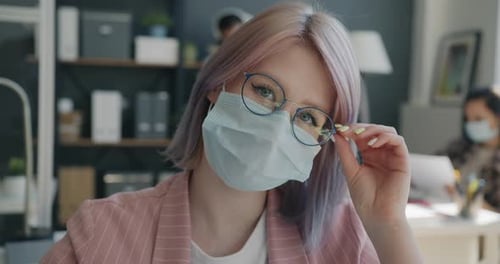 Closeup Portrait of Female Office Worker Wearing Face Mask Touching Glasses in Workplace